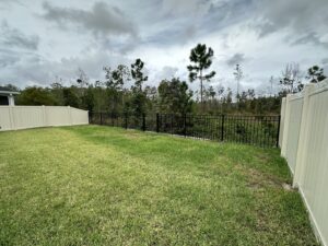 A backyard featuring a combination of tan vinyl and black aluminum fencing by Masters Fence Contracting in Jacksonville, FL.