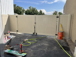A beige vinyl fence and gate installation with tools on the ground by Border Fence, Inc. in Greeley, CO.