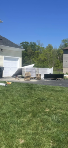Stacks of white vinyl and black metal fence materials on a driveway for Fence Pros LLC in Medford, OR.