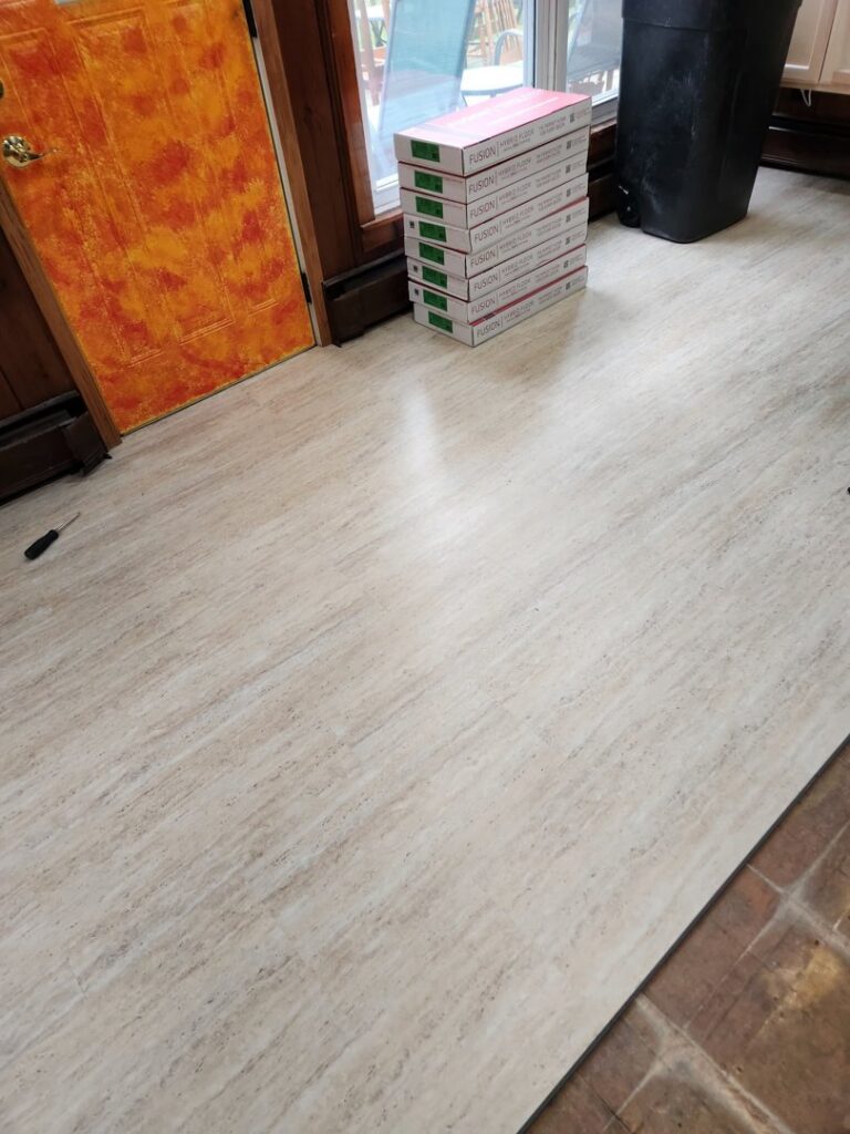 Vinyl plank flooring installation in progress with new planks and boxes on the floor by Carpet Mart Inc in Janesville, WI.