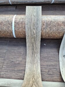 A sample of wood-look vinyl plank flooring displayed on a roll of vinyl at AFAB Carpets in Tampa, FL.