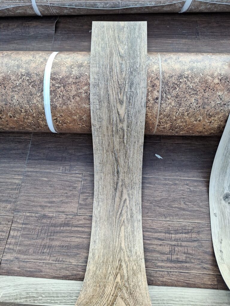 A sample of wood-look vinyl plank flooring displayed on a roll of vinyl at AFAB Carpets in Tampa, FL.