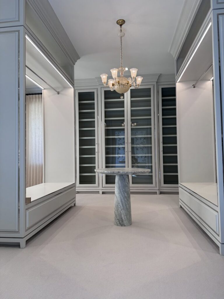 A luxurious walk-in closet featuring a chandelier and integrated shelf lighting, installed by Johnson Electric in Port Angeles, WA.