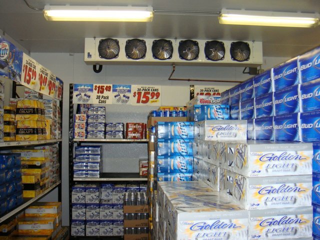 Interior of a walk-in cooler showing refrigeration units and stocked shelves by Benck Mechanical Inc in Somerset, WI.