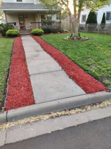 A residential walkway bordered by fresh red mulch and plants, showcasing K&R Lawn Care's landscaping services in Pass Christian, MS.