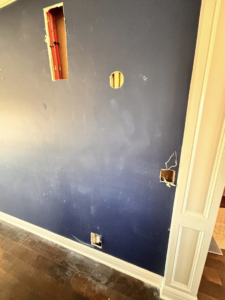 A blue wall with cutouts revealing electrical wiring conduits, showing an electrician's work by 3 Phase KC in Independence, MO.