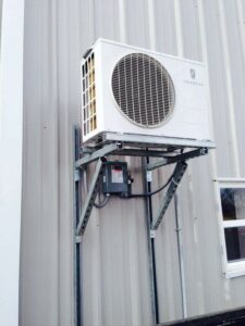A Friedrich wall-mounted outdoor AC unit installed on a metal building by Griffin's Heating & Air in Tulsa, OK.