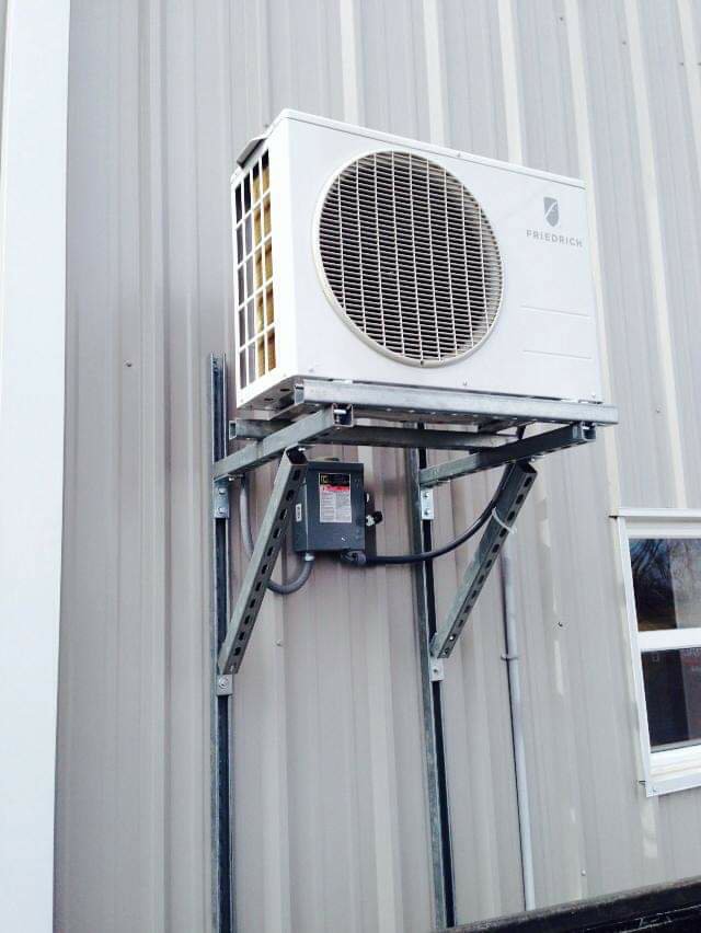 A Friedrich wall-mounted outdoor AC unit installed on a metal building by Griffin's Heating & Air in Tulsa, OK.