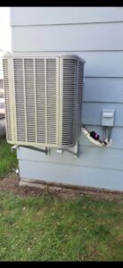 An outdoor air conditioning unit mounted on the side of a building by Preferred Heating & Air in Bismarck, ND.