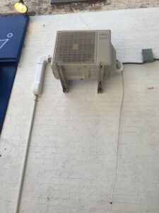 A Fujitsu outdoor mini-split condenser unit mounted on a brick wall, installed by Green Air Heating&Cooling in Philadelphia, PA.