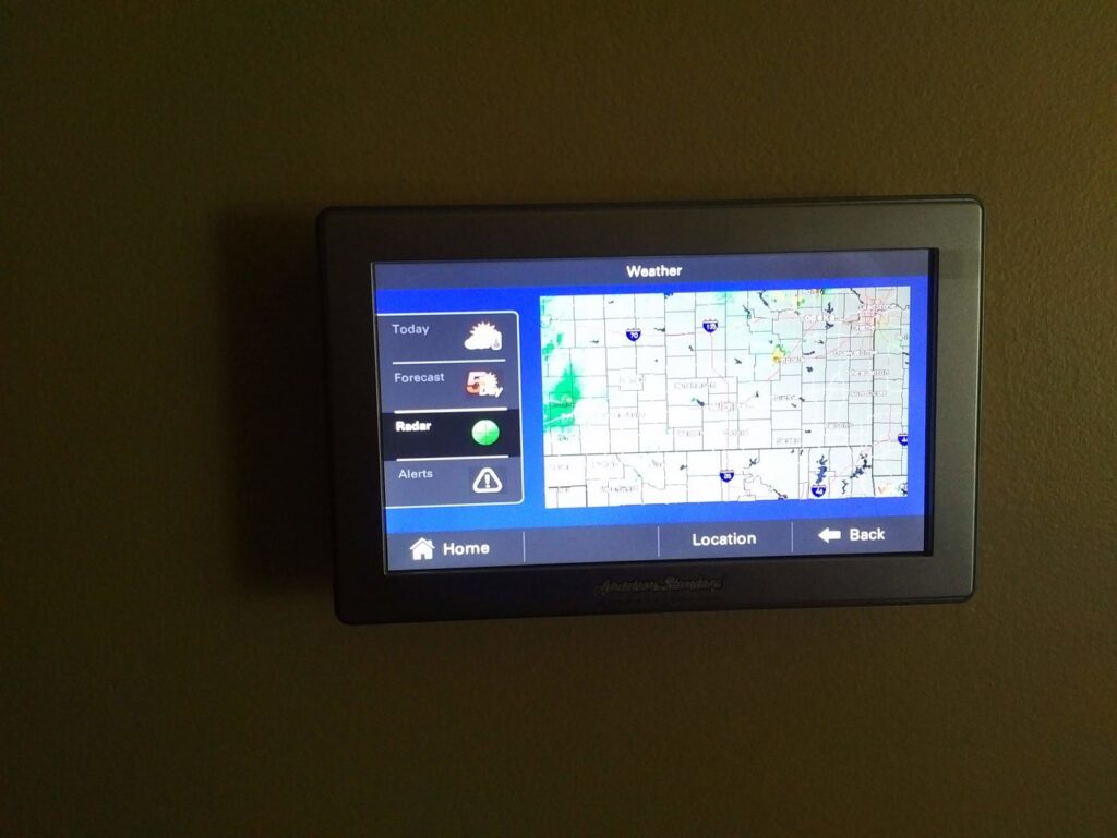 A wall-mounted smart thermostat displaying weather information, installed by Specialized Service Heat & Air in Wichita, KS.