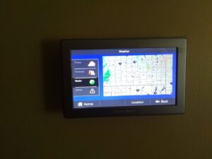 A wall-mounted smart thermostat displaying weather information, installed by Specialized Service Heat & Air in Wichita, KS.