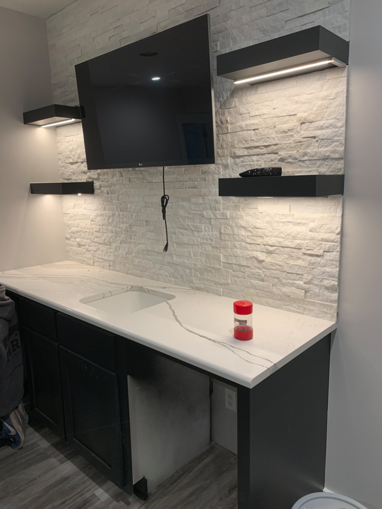 Wall-mounted TV and shelves with integrated lighting installed by Crown Enterprises Electrical Contracting in Omaha, NE.