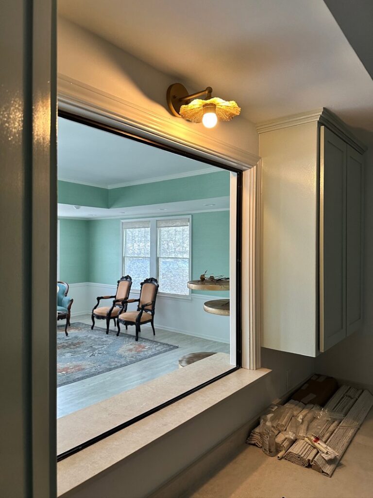 A stylish wall sconce light fixture installed above a pass-through window by LiveWire Electrical Services, LLC. in Houma, LA.