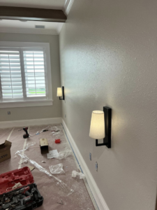 Electrician installing modern wall sconce lighting fixtures in a home, a service by ABD Electric USA in Tampa, FL.