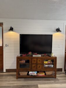 Two wall-mounted sconce lights installed above a TV in a living room by In the Light Electrical LLC in Kansas City, KS