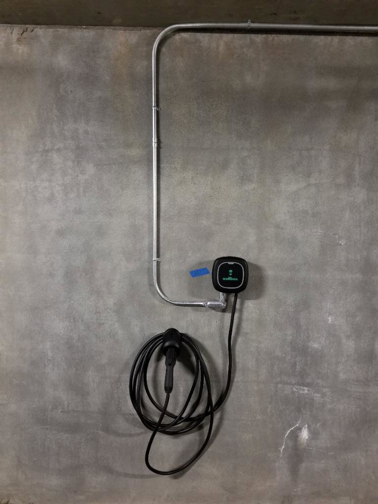 A Wallbox electric vehicle charger installed with conduit on a concrete wall by Wisdom Electrical in San Francisco, CA.
