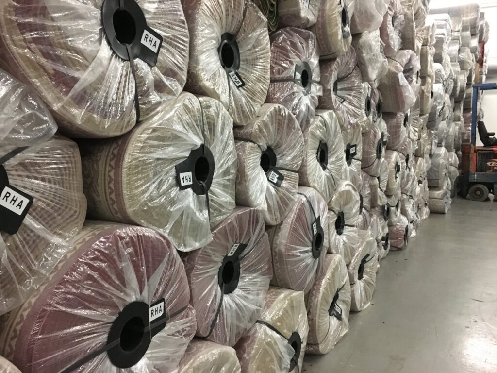 Large stack of rolled carpets in a warehouse, part of the inventory for Musalla Masjid Carpets in Glendale Heights, IL.