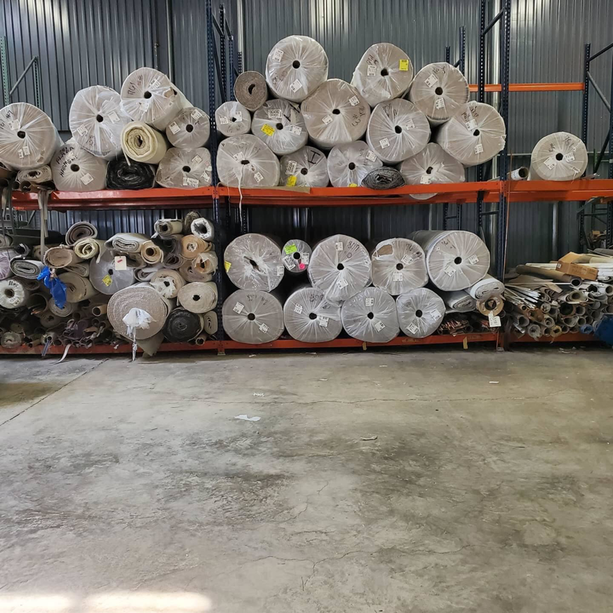 Large rolls of carpet and flooring materials stored on racks in the warehouse of TJS Floorcovering in Pennsauken, NJ.