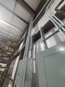 High-mounted electrical conduits and panels installed in a warehouse by Overton Power Solutions Electric in Hephzibah, GA