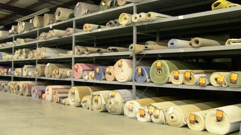 Large warehouse shelves stocked with numerous rolls of carpet at Craft Rug Mills in Easton, PA.
