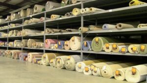 Large warehouse shelves stocked with numerous rolls of carpet at Craft Rug Mills in Easton, PA.