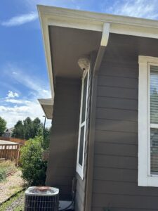 A large wasp nest visible under the eaves of a house, a common issue handled by Berrett Pest Control Denver in Denver, CO.