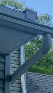 Wasps or hornets flying around a nest under a house gutter, showing a pest control situation for Pros In Control Pest Services in Jersey City, NJ.