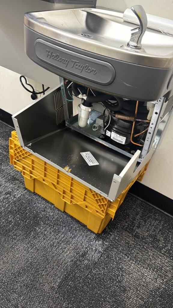 Internal components of a Halsey Taylor water cooler, showing refrigeration lines and compressor, serviced by AG Plumbing in Pittsburgh, PA.