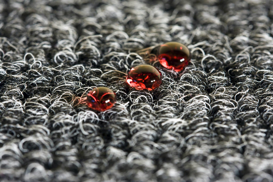 Close-up of water droplets on a dark carpet, showcasing water protection by Xtreme Clean Restoration & Carpet Care in San Antonio, TX