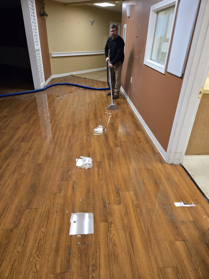 A technician performing water extraction from a wet hardwood floor by Aardvark Dean Of Clean in Nashua, NH.