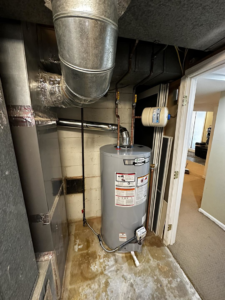 A water heater and extensive HVAC ductwork visible in a basement utility area by Adonis Hvac in Annapolis, MD.