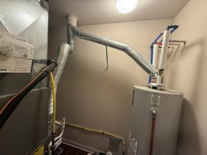 A newly installed water heater and furnace with ductwork in a utility closet by Northern Peak Heating & Cooling in Bozeman, MT.