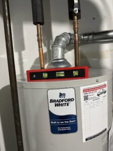 A level placed on a Bradford White water heater, indicating professional plumbing installation by All Comfort Services in Madison, WI