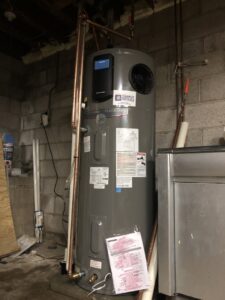 A newly installed water heater with a Simply Installs Heating & Air Conditioning sticker, located in Shortsville, NY.