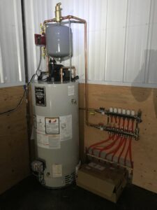 A water heater connected to a radiant heating manifold system, installed by Simply Installs Heating & Air Conditioning in Shortsville, NY.