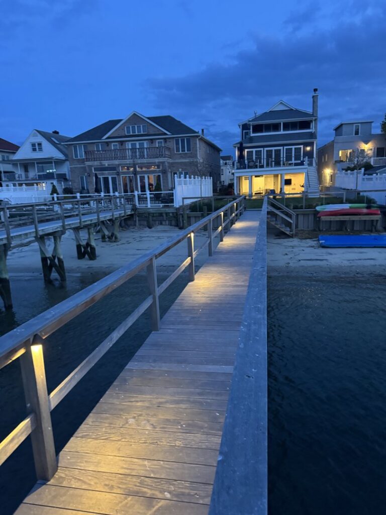 Waterfront homes and a dock with installed pathway lighting at dusk, a service provided by New York Electrical Design in Freeport, NY