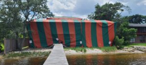 A waterfront house covered in a red and green fumigation tent by Rivers Pest Control Service, Inc. in Jacksonville, FL