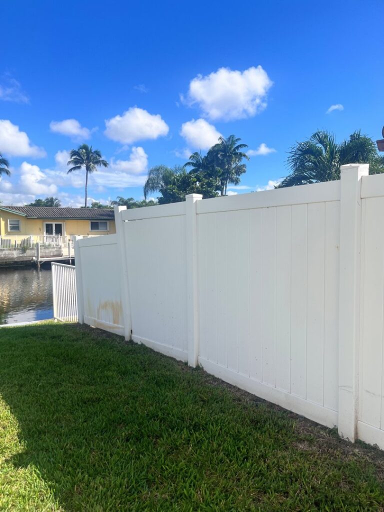 A white vinyl fence installed along a sunny waterfront property by Ace Fence Company in Fort Lauderdale, FL.