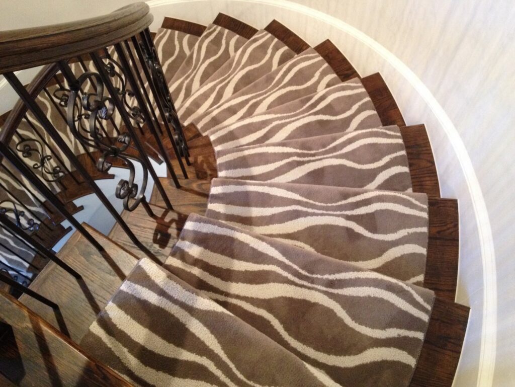 A modern wavy patterned carpet runner expertly installed on a spiral staircase by Carpet Binding Company in Charlotte, NC.