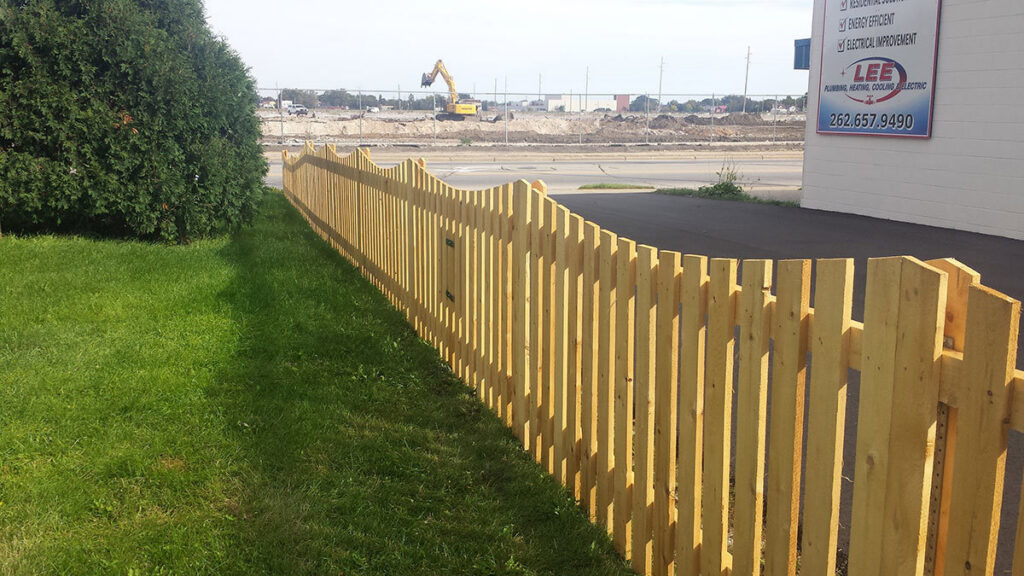 A long, decorative wavy-top wooden picket fence installed for a commercial property by Statewide Fencing, Inc. in Racine, WI.