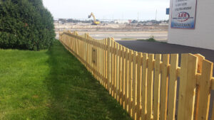 A long, decorative wavy-top wooden picket fence installed for a commercial property by Statewide Fencing, Inc. in Racine, WI.