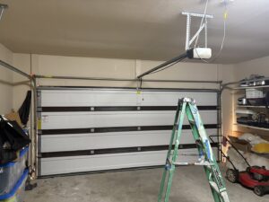 Close-up of a Wayne Dalton garage door track with a Cajun Doors & More contact sticker, showing quality products used in Lafayette, LA.