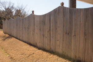 A weathered wood fence with a decorative scalloped top, showcasing a past installation by Top Rail Fence Birmingham, AL