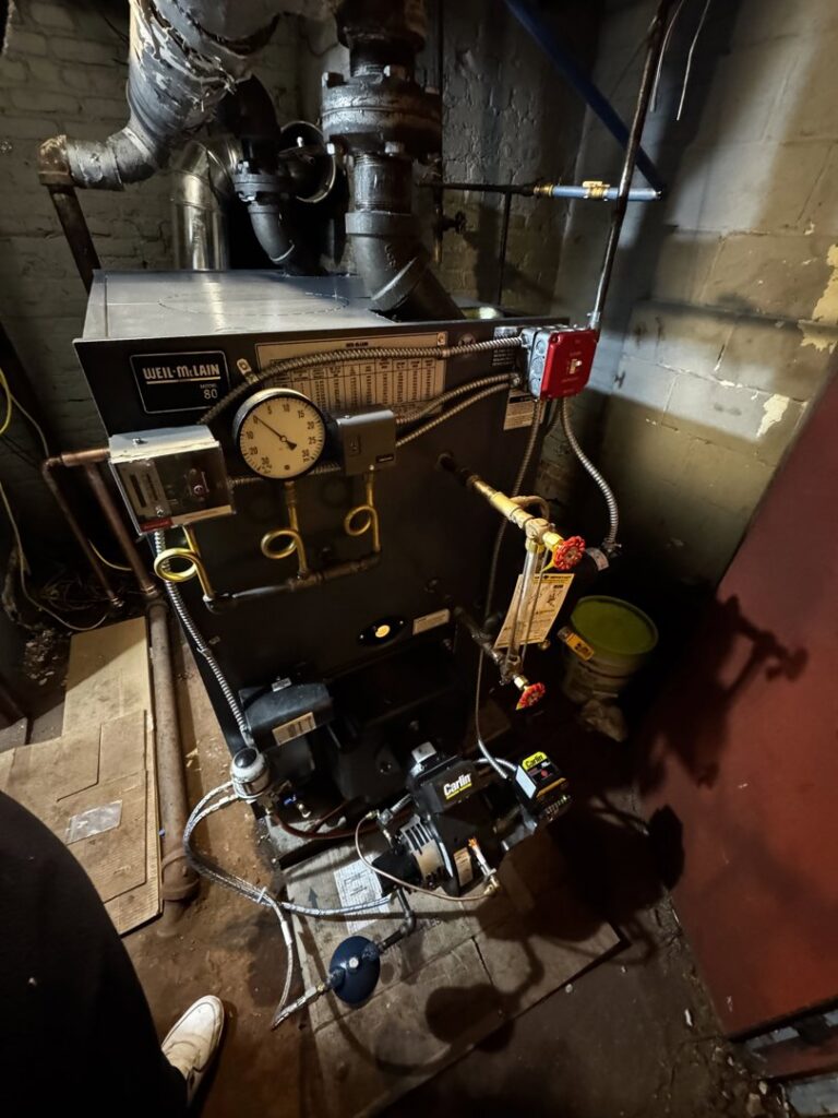 A Weil-McLain boiler with a Carlin oil burner installed in a utility room by L&SON Heat AC Tech in Yonkers, NY.