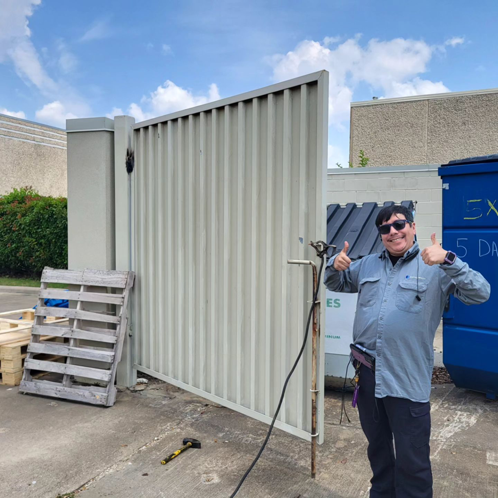 A Dallas Mobile Welder, LLC. contractor giving a thumbs up next to a newly installed commercial gate in Dallas, TX.