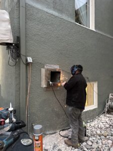 A technician welding a metal vent or ductwork into a wall during an HVAC installation by CHAMPS Heating&Air in Denver, CO