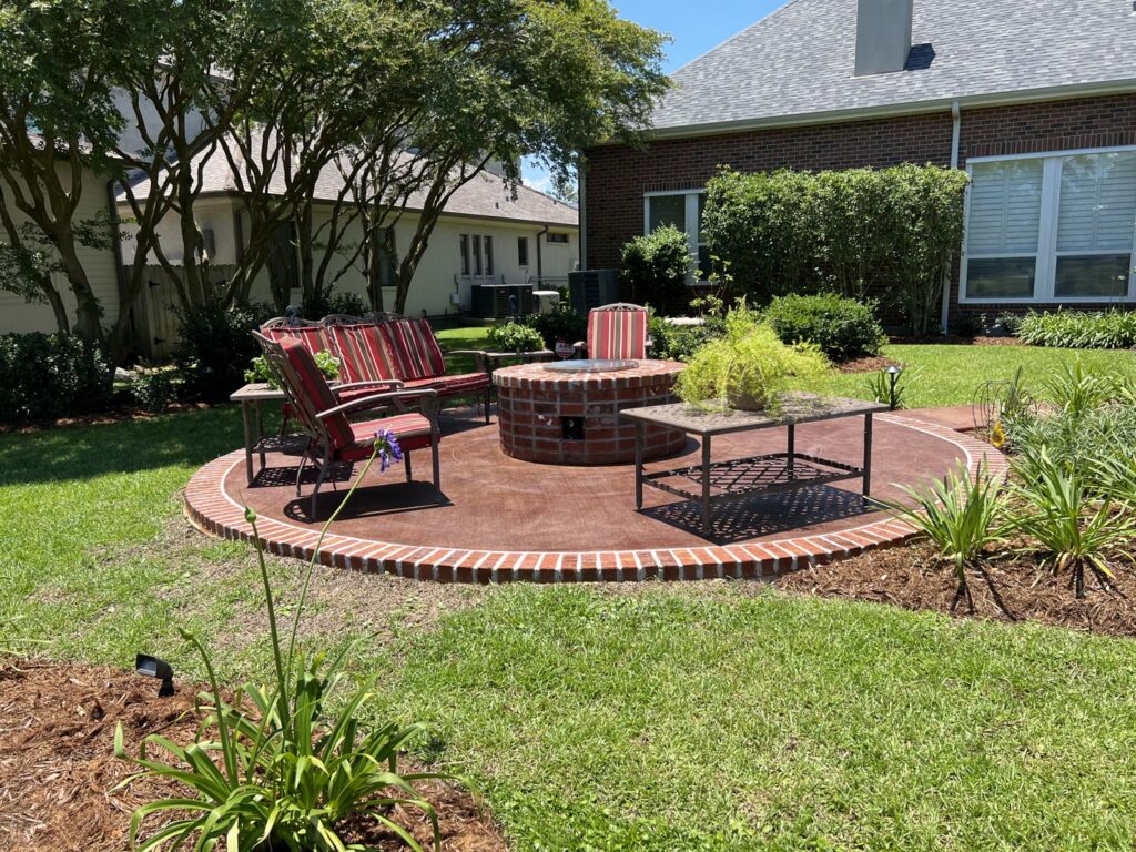 A well-maintained backyard with a circular patio, fire pit, and green lawn by Fresh Cuts Nola Lawn Service in New Orleans, LA.