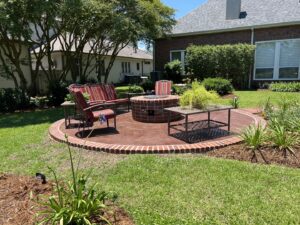 A well-maintained backyard with a circular patio, fire pit, and green lawn by Fresh Cuts Nola Lawn Service in New Orleans, LA.