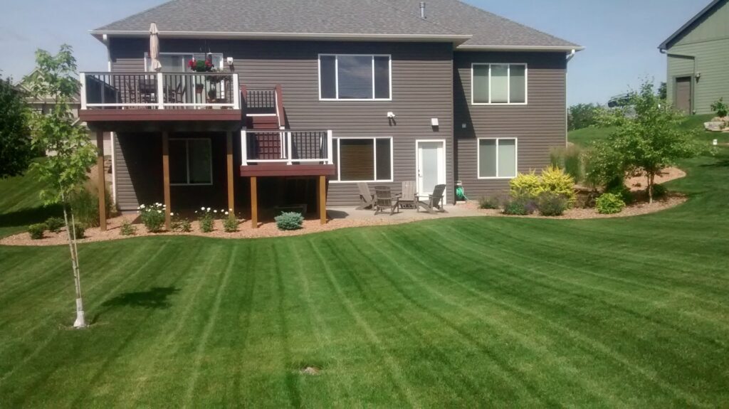 A well-maintained backyard with a mowed lawn and patio area, expertly cared for by Three Boys Lawncare in Rochester, MN.